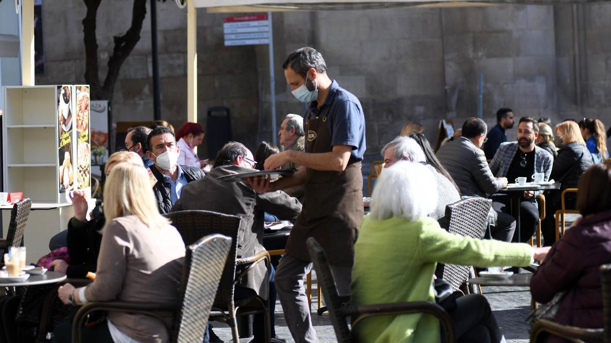 Personas toman algo en una terraza en Belluga.