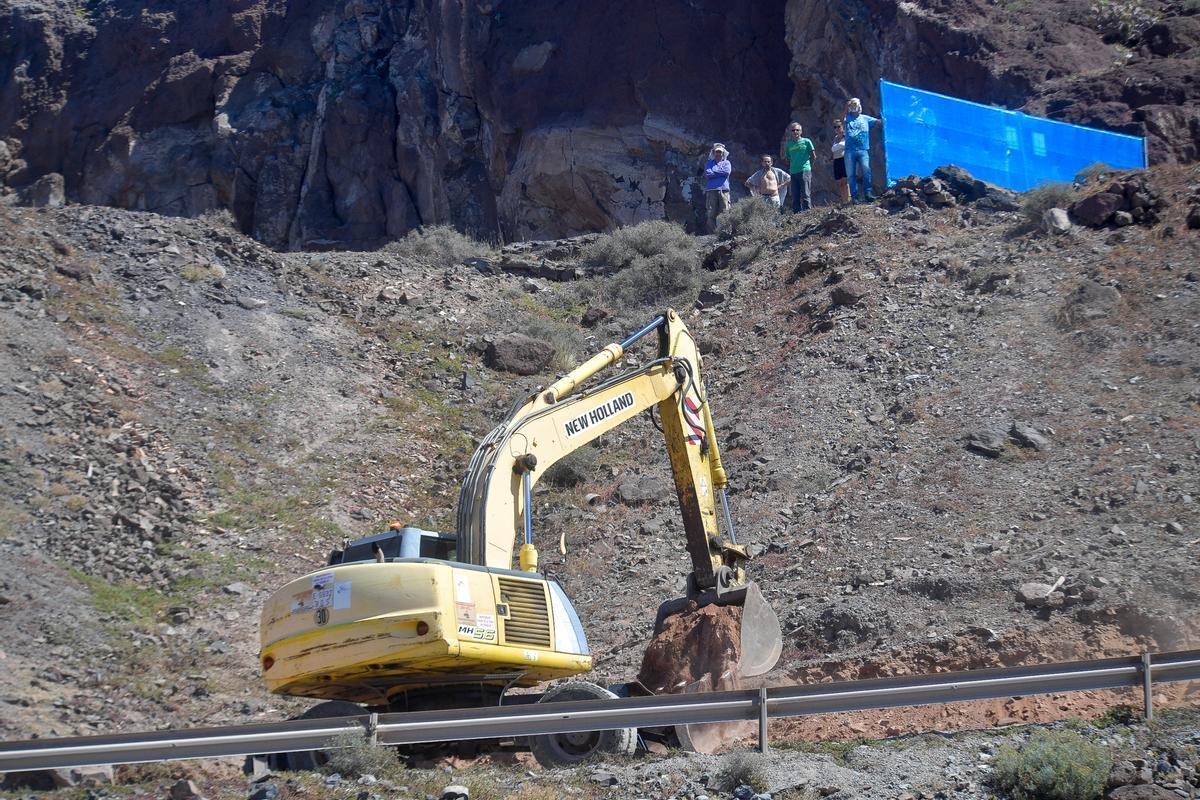 La excavadora trabaja ante la atenta mirada de los activistas en la parte superior de la ladera.