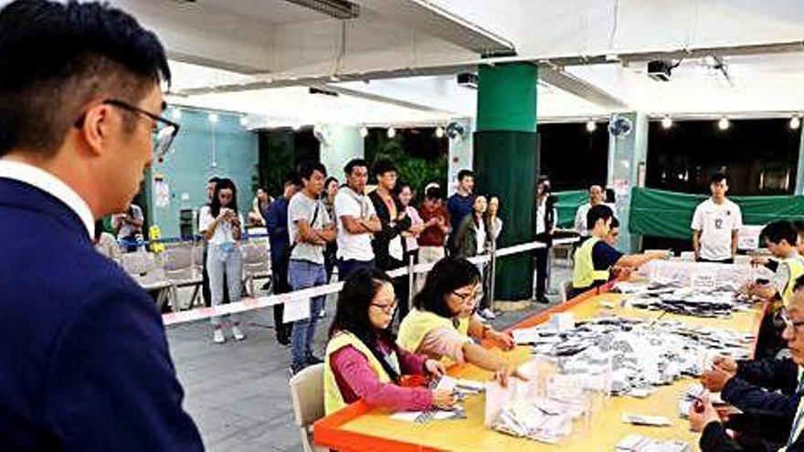 Un candidat local observa com els funcionaris compten els vots en una mesa electoral a Kowloon Tong