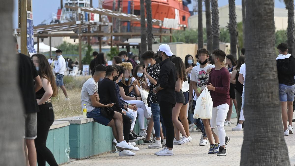 Jóvenes hacen botellón y charlan en el paseo y la playa del Arenal de Burriana.