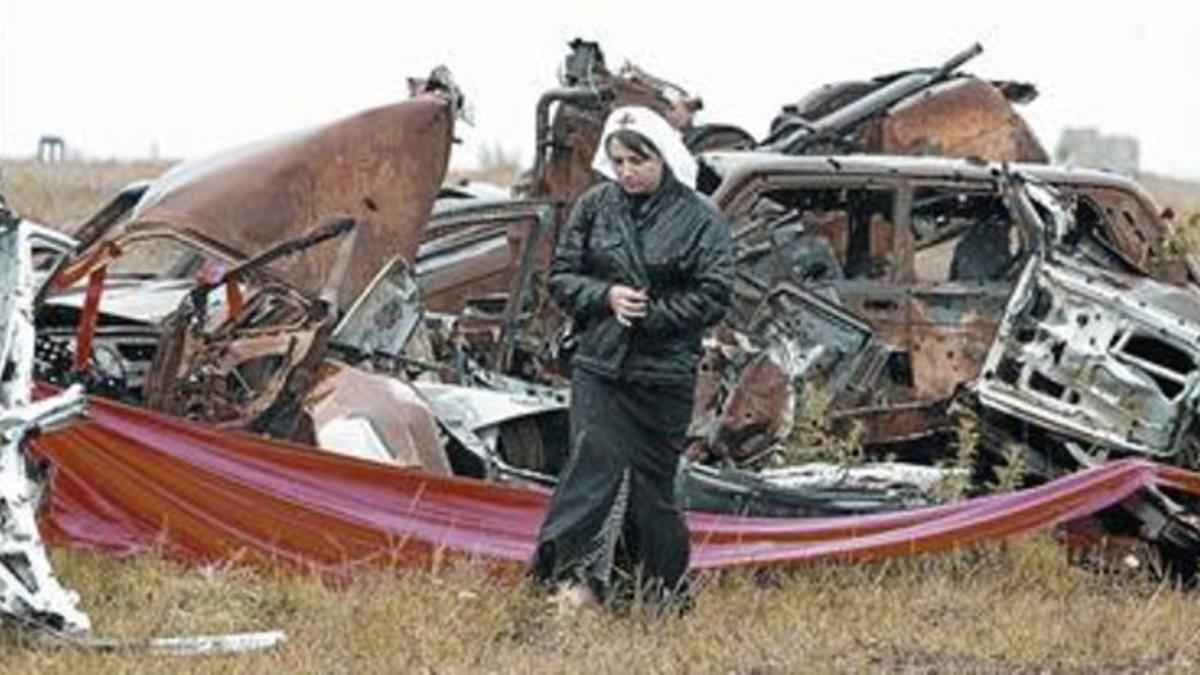 Una enfermera junto a restos de coches quemadas que aún no han sido retirados de las afueras de Tsjinvali.