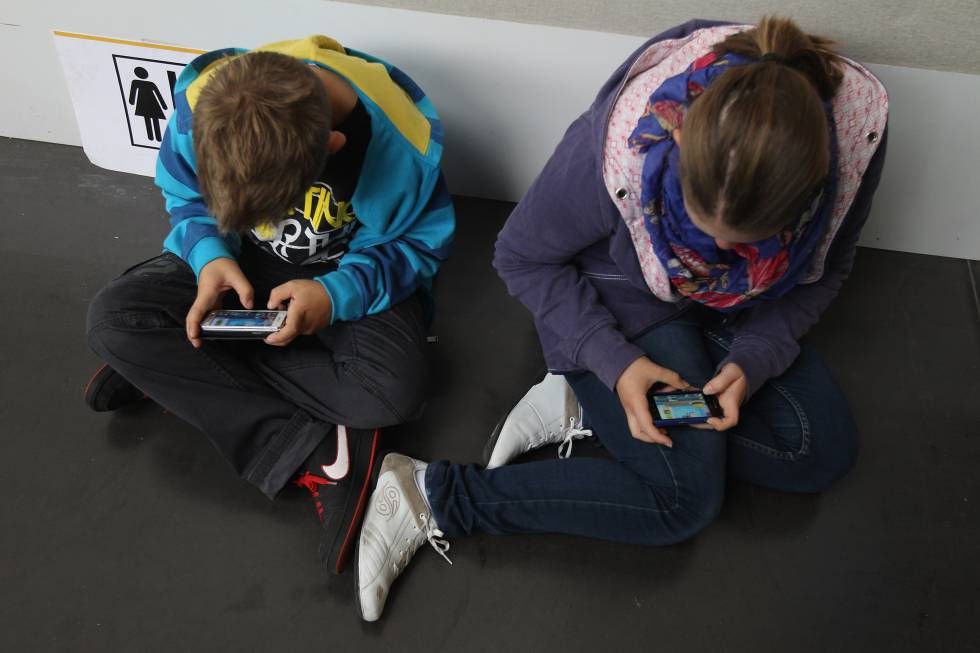 Dos niños atentos a la pantalla de su móvil
