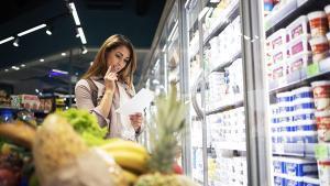Una mujer repasando su lista de la compra en un supermercado.