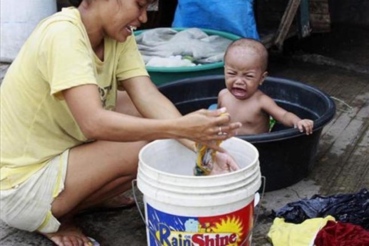 Un nen plora mentre la seva mare renta la roba en un assentament d’ocupants il·legals al districte de Tondo, a Manila (Filipines).
