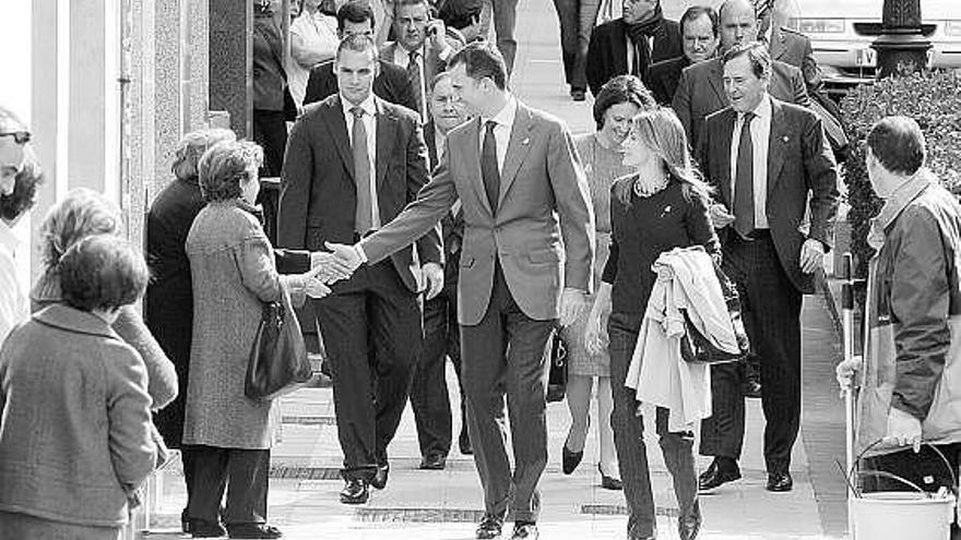 Don Felipe estrecha la mano de una ciudadana durante el breve paseo desde la sede de la Fundación al Reconquista. A su lado, doña Letizia. Tras ellos, Teresa Sanjurjo y Matías Rodríguez Inciarte.