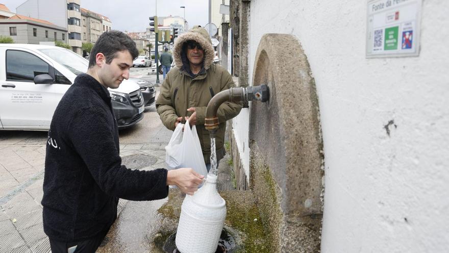 Dos hombres llenan sus garradas
en la fuente de Fenosa. | Alba Villar
