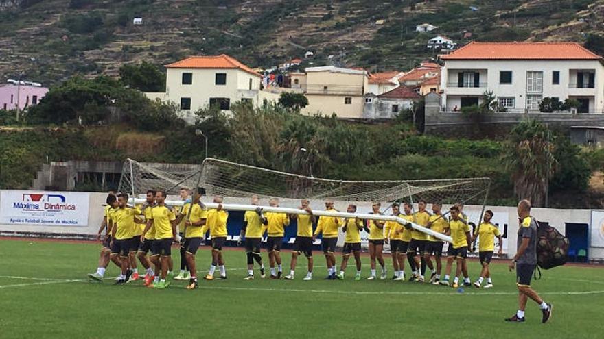 El plantel de la UD, con Mauricio Lemos a la cabeza, porta una de las porterías, en la Ciudad Deportiva de Machico, ayer, en Madeira. A la derecha, el preparador físico, Rafa Cristóbal.