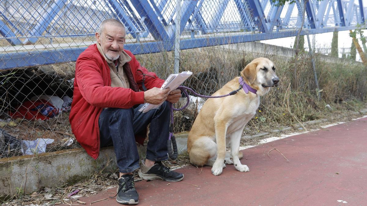 Sebastián González, junto a su perra y algunas de sus pertenencias, en el puente donde vive.