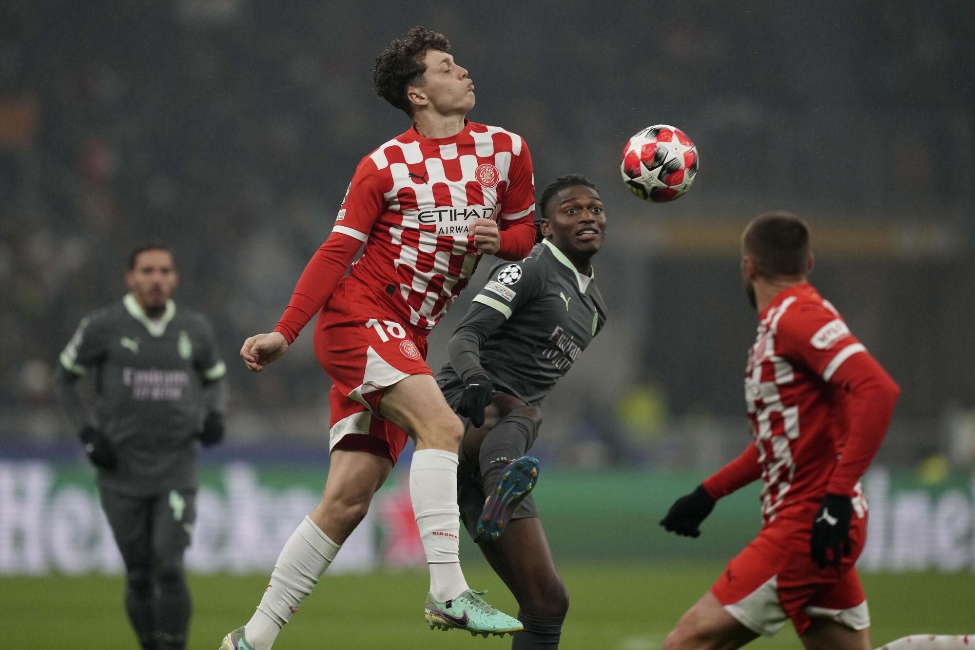 Girona's Ladislav Krejci, centre left challenges for the ball with AC Milan's Rafael Leao, centre right during the Champions League opening phase soccer match between AC Milan and Girona at the San Siro stadium in Milan, Italy, Wednesday, Jan. 22, 2025. (AP Photo/Antonio Calanni). EDITORIAL USE ONLY/ONLY ITALY AND SPAIN