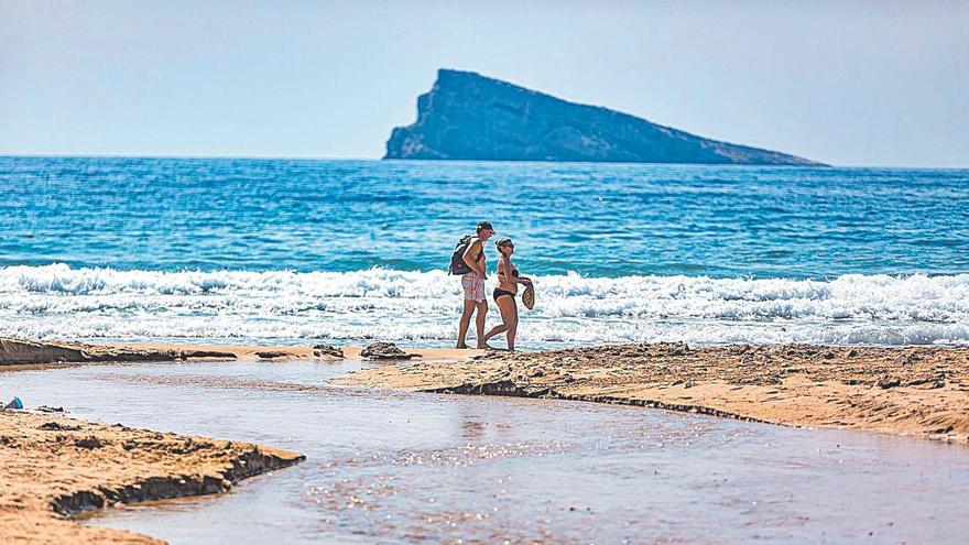 Una pareja de turistas pasea por la playa de Levante de Benidorm.