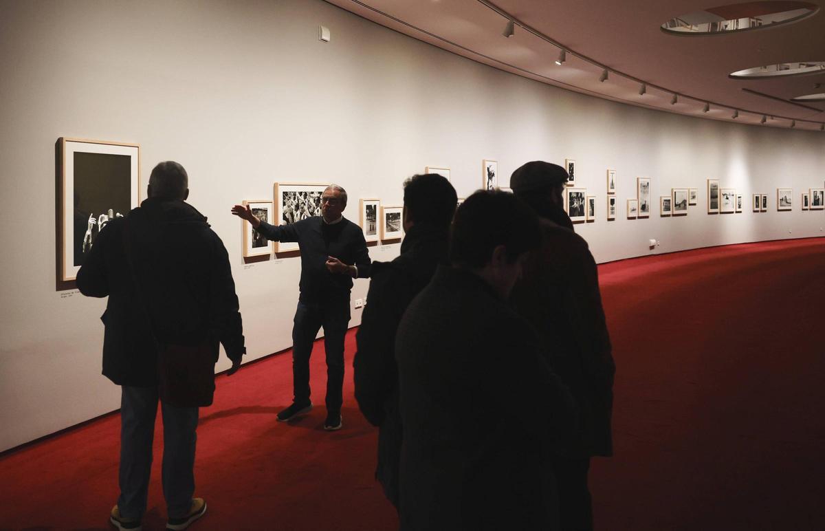 Chema Conesa explica las fotos de Ramón Masats en el "foyer" del auditorio del Niemeyer.