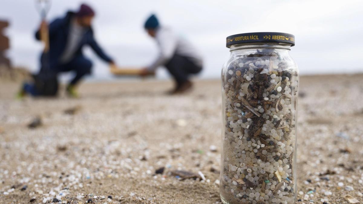 Varias personas recogen pellets llegados a playas de Tarragona.