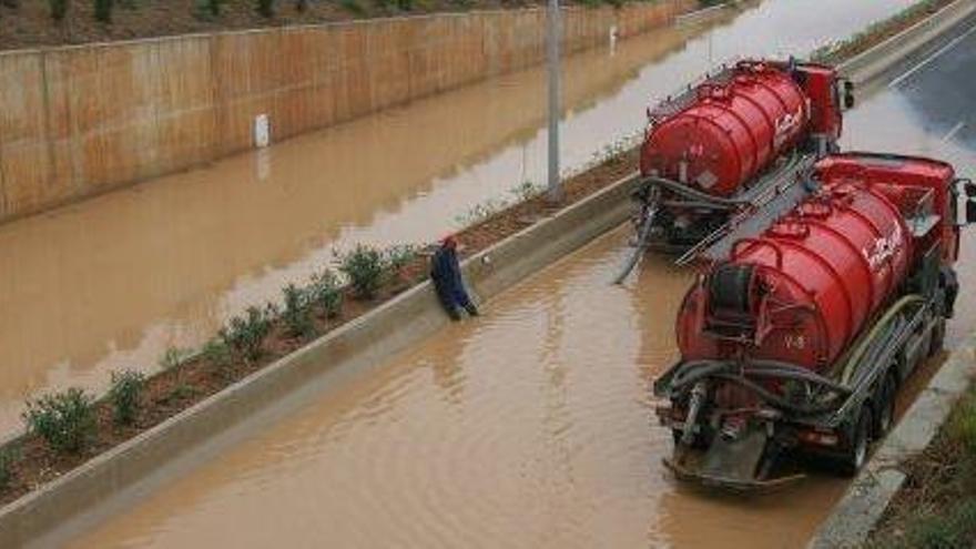 Dos camiones cisternas evacúan el agua acumulada durante una de las inundaciones de la autovía.