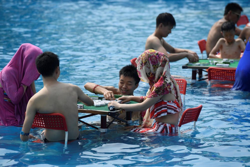 La gente sumerge las mesas y sillas en el agua en un día caluroso en un parque acuático de Chongqing, China