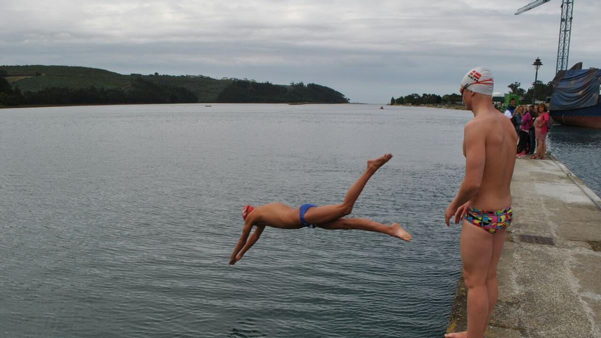 Dos nadadores lanzándose a la ría de Navia desde el dique dañado en una imagen de archivo.