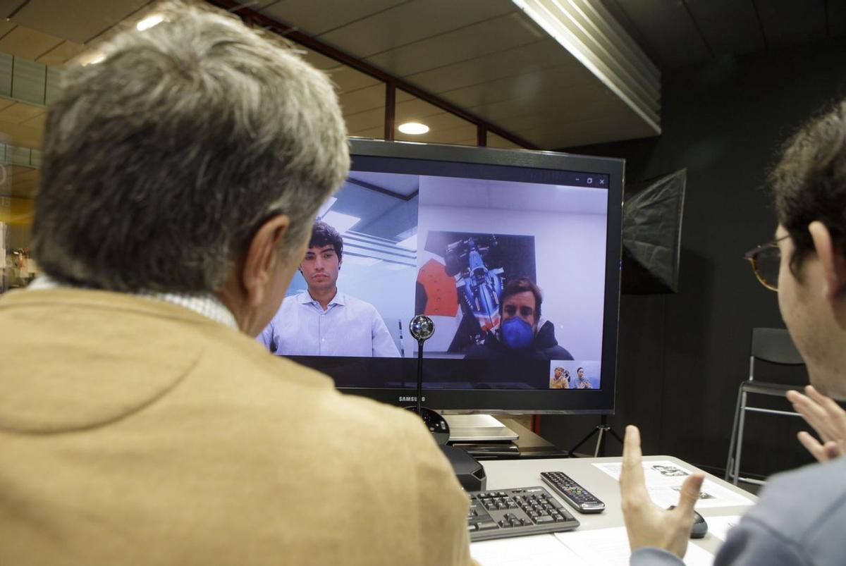 En la pantalla, por la izquierda, Fernando Poveda, jefe de comunicación producto  Renault y Alpine, y  Fernando Alonso, ayer, en un momento de la entrevista. En la imagen inferior, el ovetense muestra su tatuaje con la Cruz  de la Victoria. |  Fernando Rodríguez