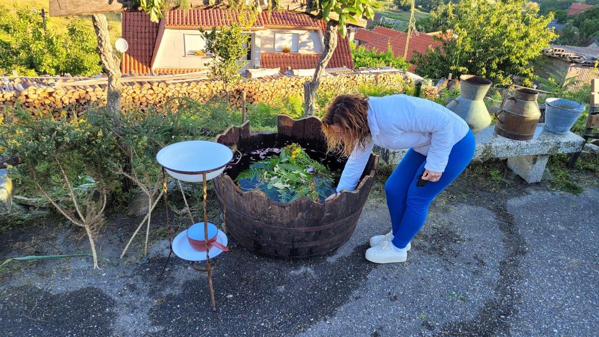 Una mujer recoge el &quot;agua mágica&quot; del barreño, ayer, en la plaza de Arcade de Riba. / José Valdivia