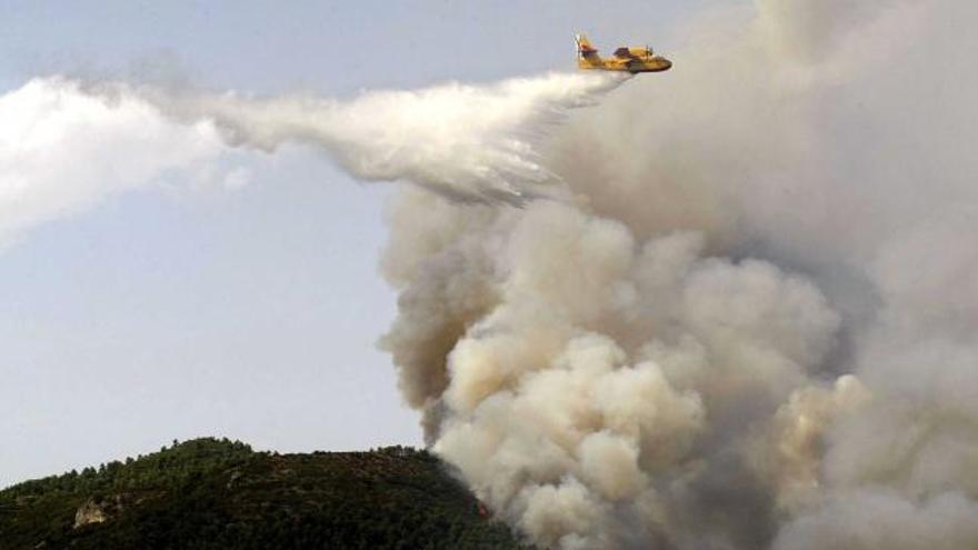 Por tierra y aire contra el fuego.  Un hidroavión descarga agua sobre la zona afectada por el fuego en Torremanzanas, en Alicante. Ocho helicópteros y seis aviones participaron ayer en las tareas de extinción.