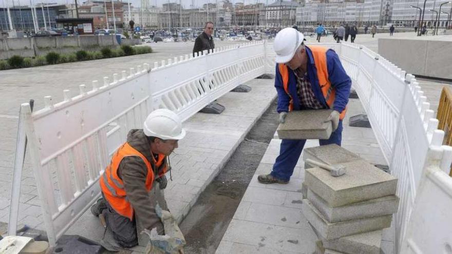 Dos obreros reemplazan el pavimento de la explanada de O Parrote.