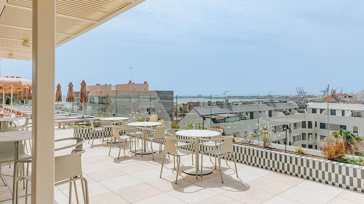 La terraza de la azotea reúne mesas al aire libre y vistas sobre el paisaje urbano y marítimo de Valencia.