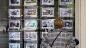 Imagen de archivo con una mujer mirando la oferta de viviendas en una inmobiliaria de Bilbao.