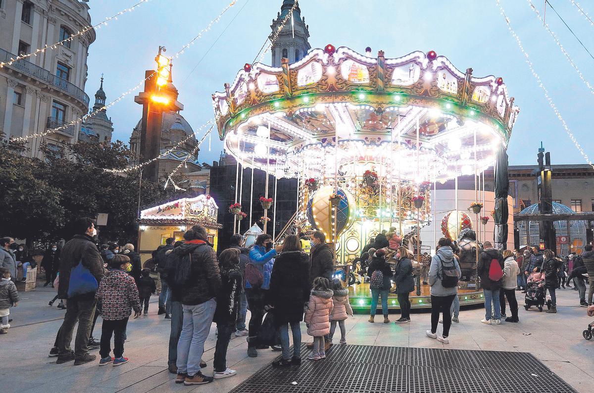 Varios niños esperan para montar en un tiovivo del centro de Zaragoza.