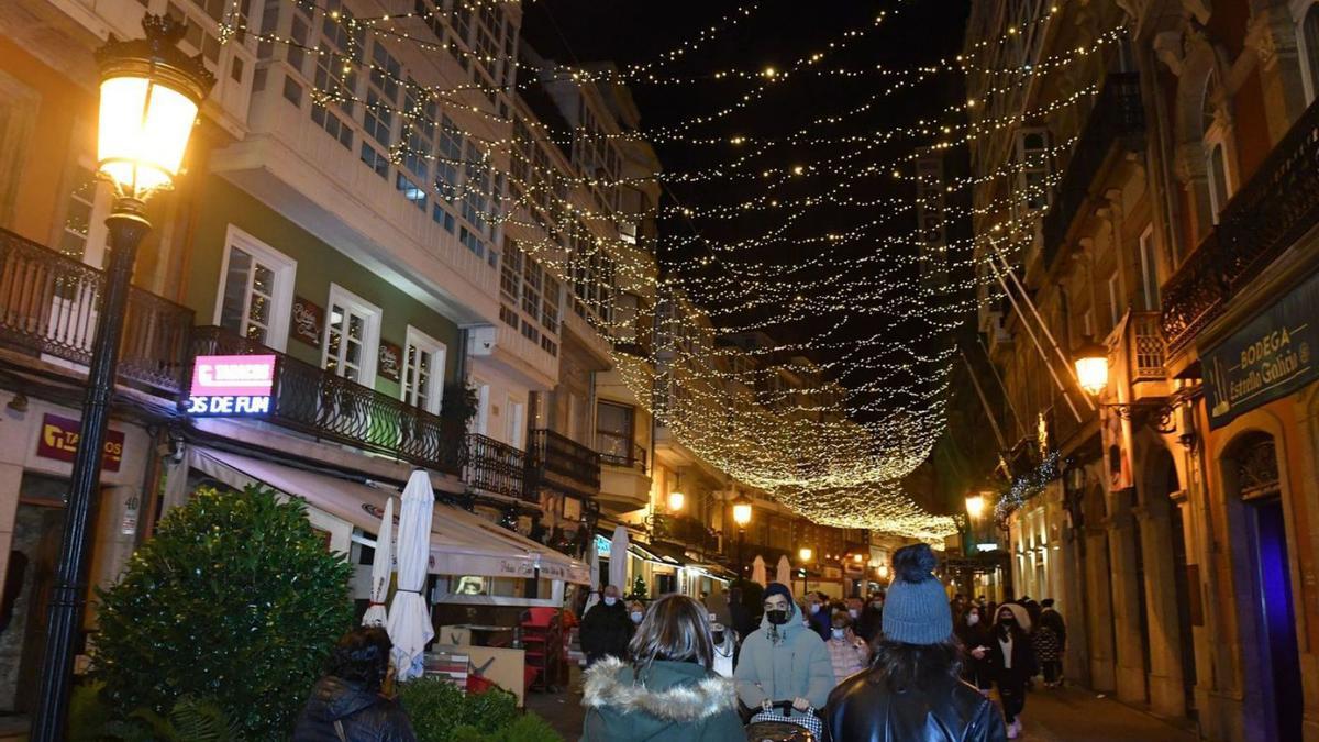 Ciudadanos caminan bajo el alumbrado navideño en la calle Riego de Agua, en A Coruña.  | // VÍCTOR ECHAVE