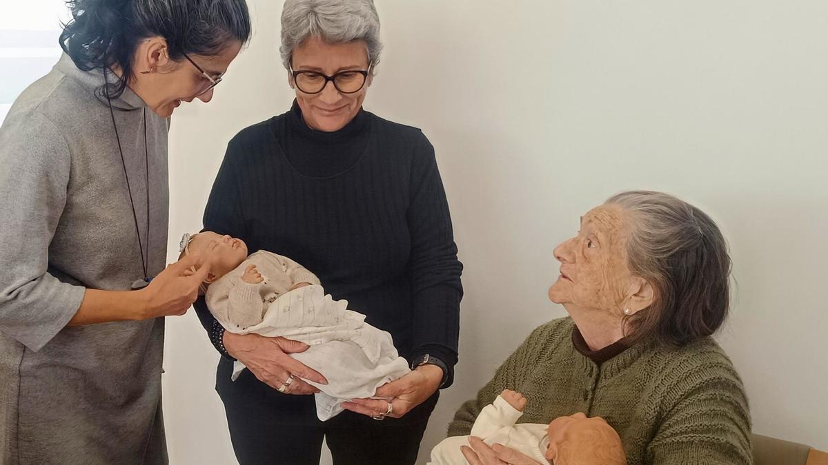 Una de las usuarias del centro de Guadassuar sositene una de las muñecas donadas,  junto a Maribel y su hija.