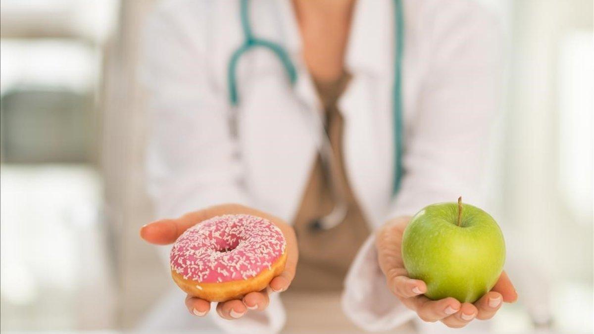 Una doctora ofreciendo un donut y una manzana