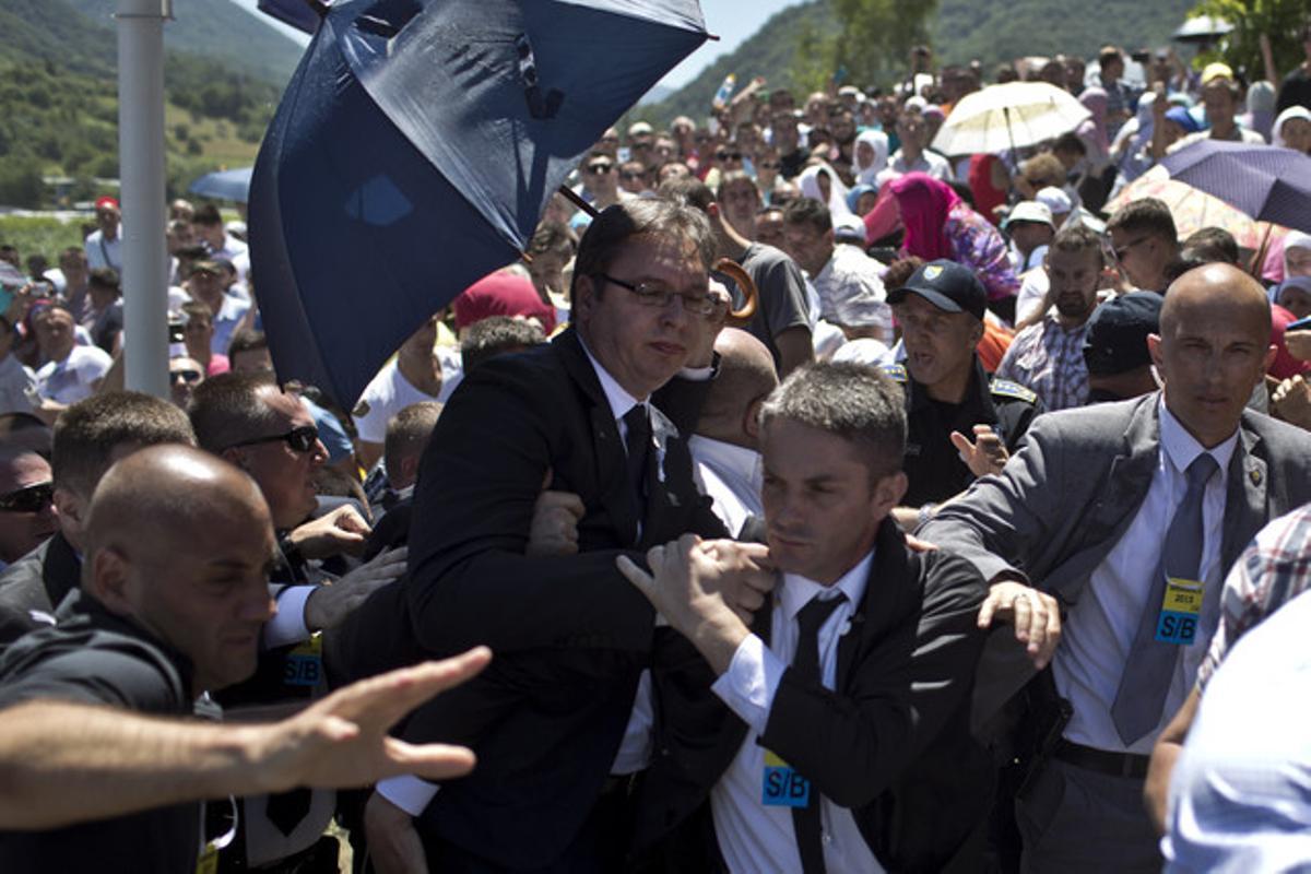 Aleksandar Vucic, primer ministro serbio, protegido por sus guardaespaldas en el momento de ser agredido en el homenaje a los muertos en la masacre de Srebrenica