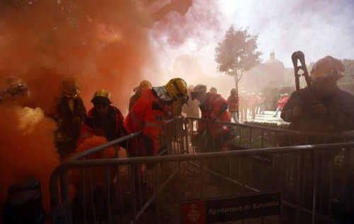 Fireman remove fences at the Catalunya's Parliament among red smoke during a protest against budgets cuts in Barcelona