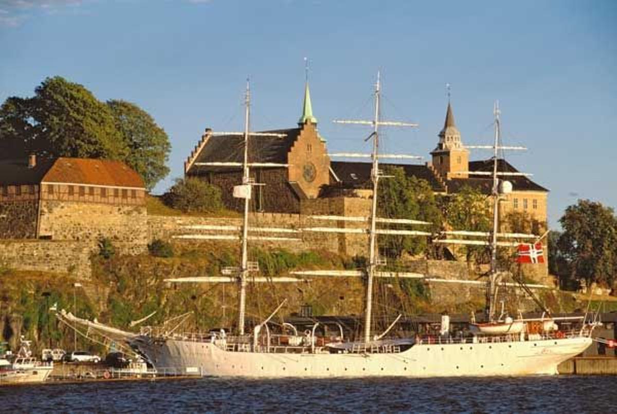 Vista de la Fortaleza de Akershus con un barco de vela al frente.