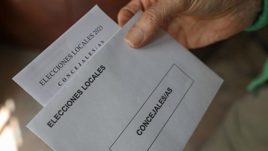 Una persona muestra el sobre y una de las papeletas que pueden ser depositadas en las urnas en las elecciones municipales de este 28 de mayo.