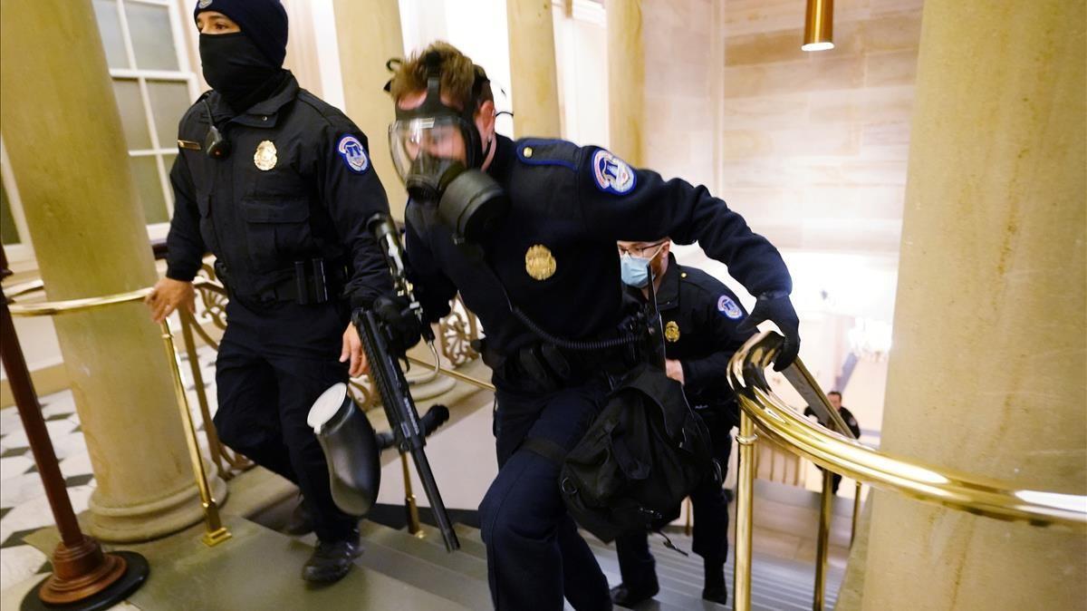 Refuerzos de la policía entran en el Capitolio para contener a los manifestantes pro-Trump que han irrumpido en el edificio.