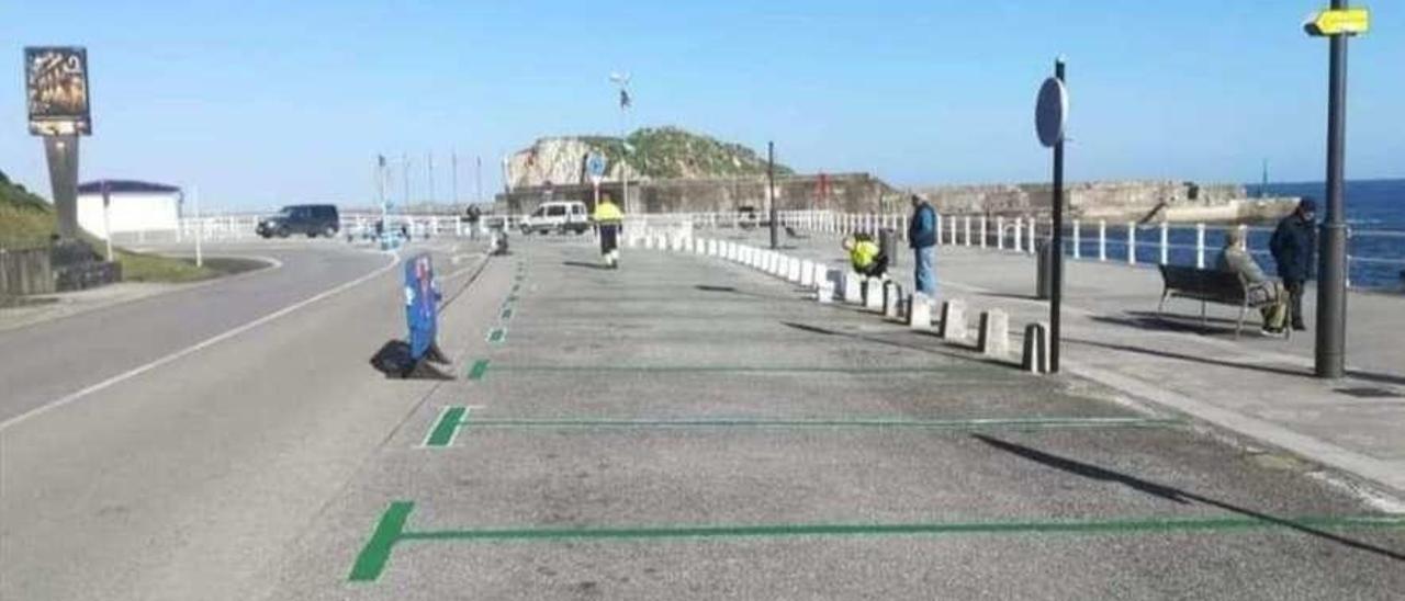 Trabajadores pintando la nueva zona de aparcamientos en la entrada de la villa pixueta por el puerto.