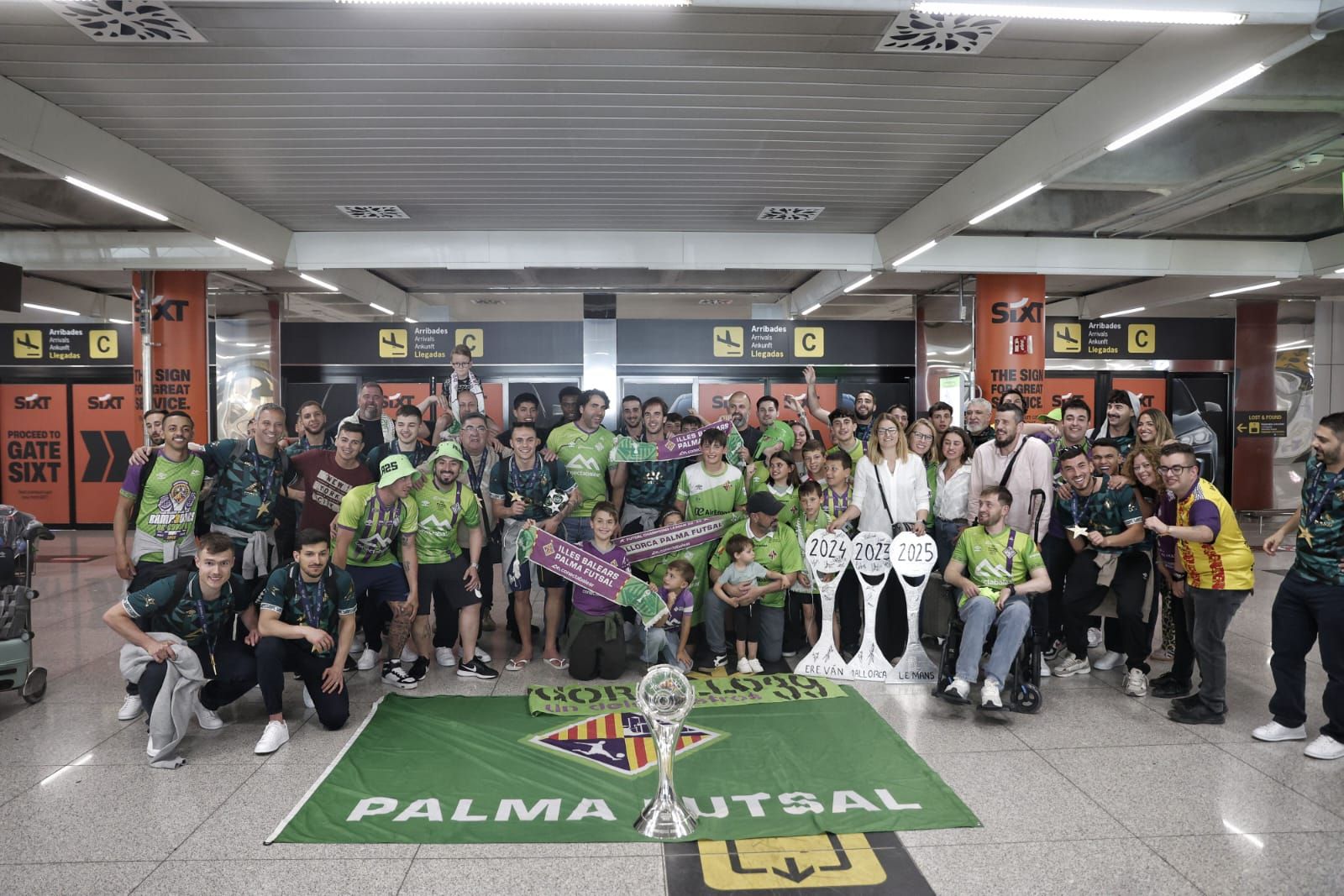 Medio centenar de aficionados reciben al Palma Futsal a su llegada a la isla tras conquistar la Champions