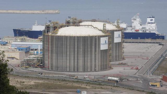 El «Gaslog Wellington», atracado en la terminal de la regasificadora de El Musel la semana pasada, con los dos tanques de almacenamiento de Musel e-Hub y un camión cisterna en el cargadero,  en primer término. | JUAN PLAZA