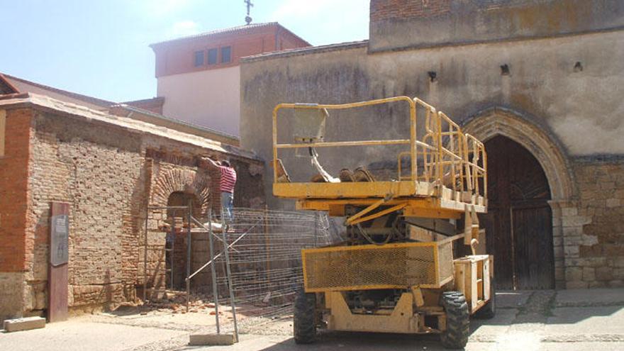 Un operario trabaja en la restauración de uno de los muros de la iglesia de San Pedro del Olmo.