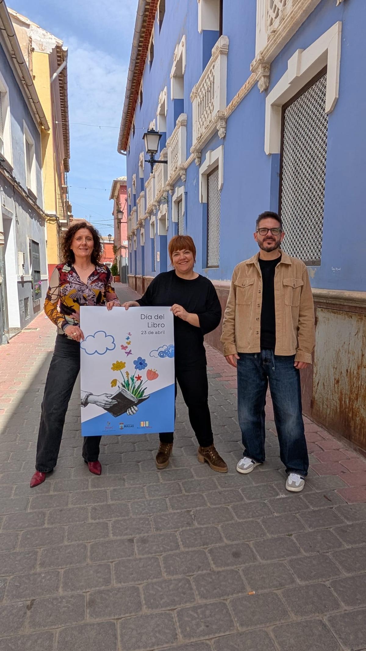 El concejal de Cultura junto con las bibliotecarias sosteniendo el cartel