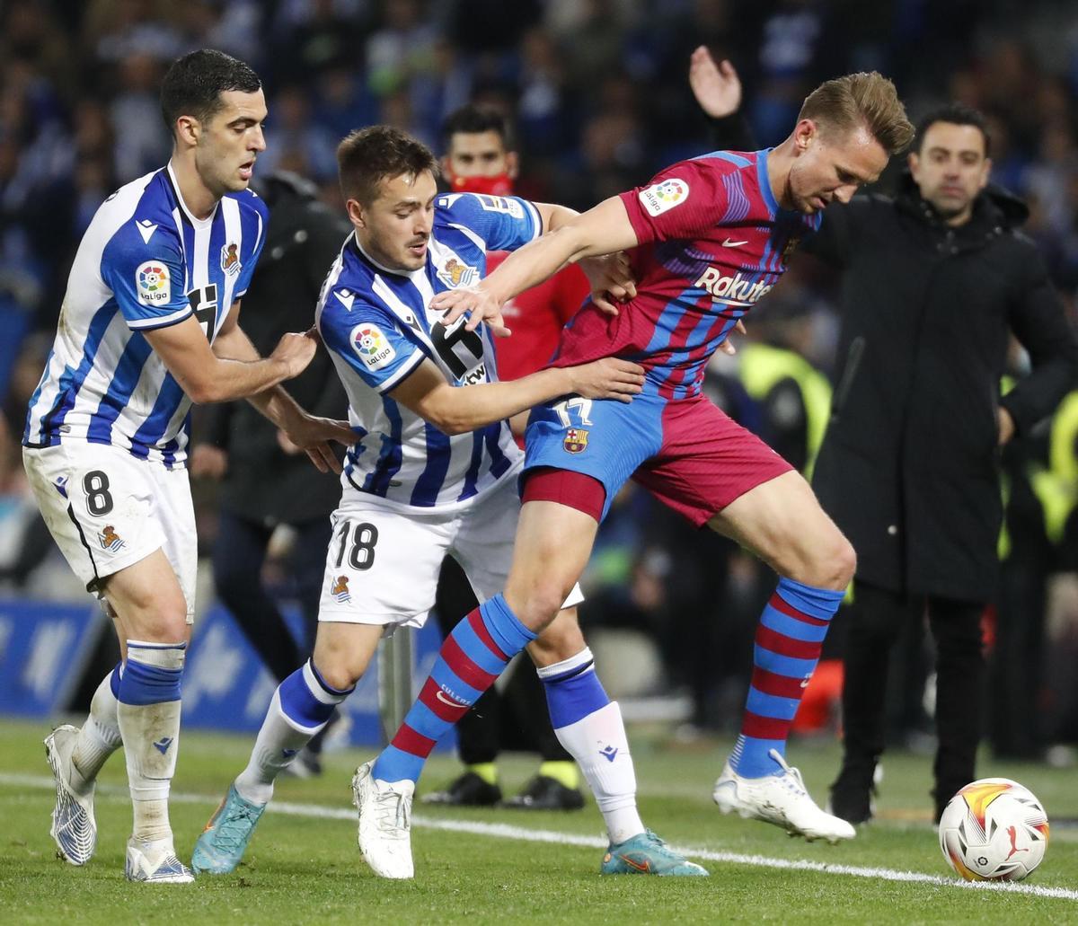 SAN SEBASTIÁN, 21/04/2022.- El delantero neerlandés del FC Barcelona, Luuk de Jong (d), protege el balón ante los jugadores de la Real Sociedad, Andoni Gorosabel (c) y Mikel Merino, durante el encuentro correspondiente a la jornada 33 disputado hoy jueves en el Reale Arena de San Sebastián. EFE / Juan Herrero.