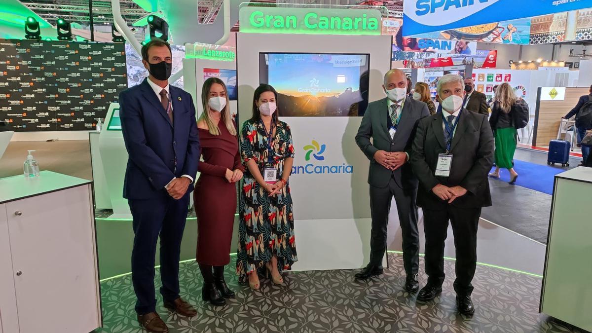 La consejera de Turismo, Yaiza Castilla, y otras autoridades, junto a una pantalla que promociona Gran Canaria en la Feria de Turismo de Londres.