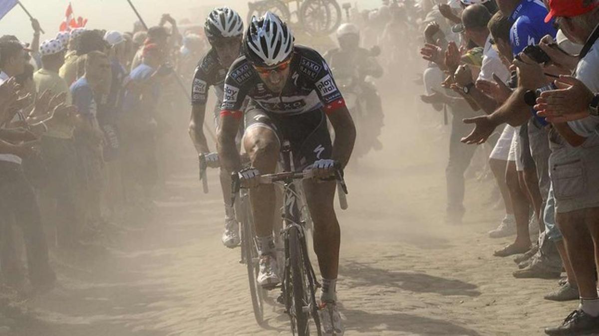 Los ciclistas de Saxo Bank Fabian Cancellara y Andy Schleck (atrás), en un tramo adoquinado de la tercera etapa.