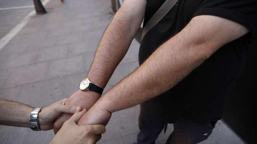 El educador de calle de Cáritas coge las manos de uno de los sin hogar a los que atiende a diario.