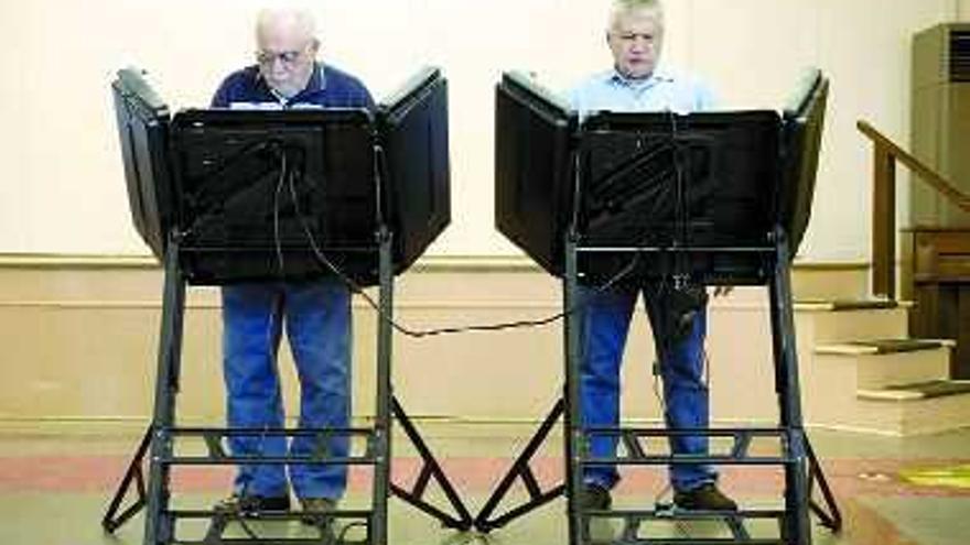 Dos hombres utilizan el nuevo sistema electrónico de votación en un colegio de la localidad de Palmyra. / efe