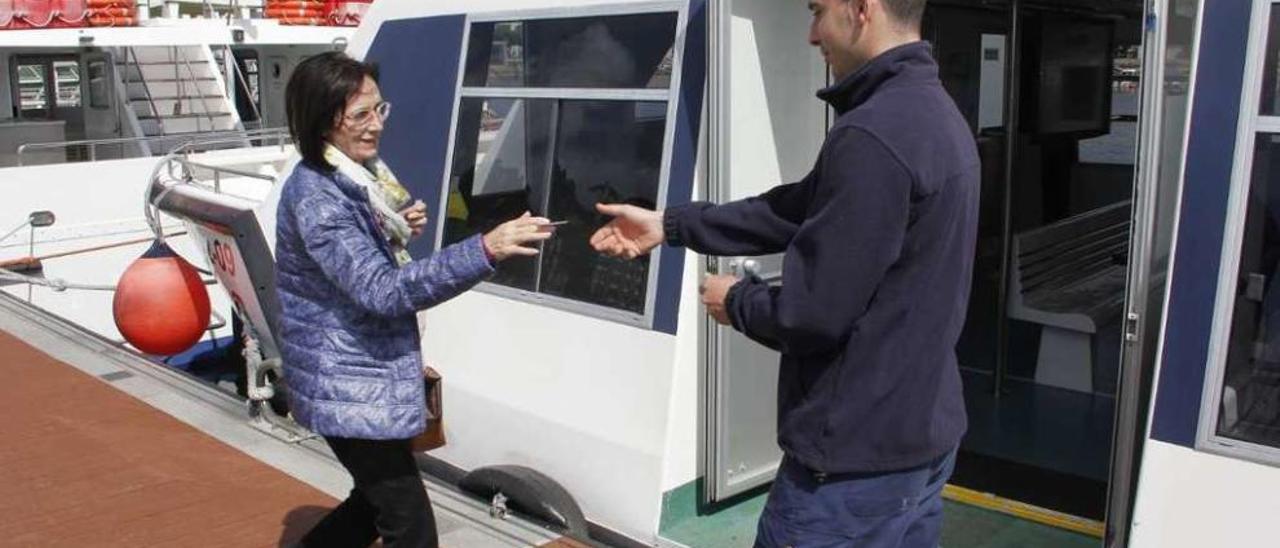 Una usuaria entrega la tarjeta metropolitana para subir a un barco del transporte de ría en Cangas. // S.A.