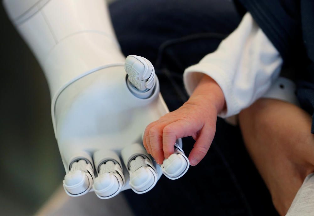 El robot "Pepper", diseñado para acoger y cuidar a pacientes y visitantes, tiende la mano a un bebé recién nacido en un hospital de Bélgica