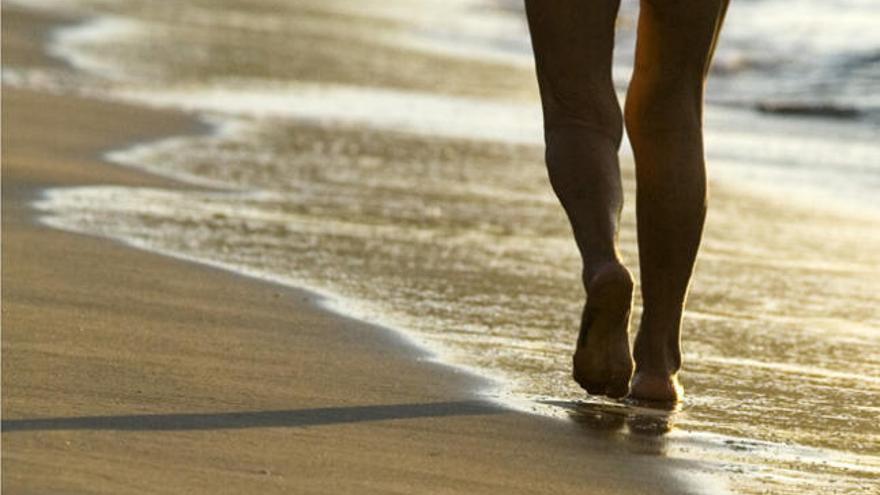 Una mujer pasea por la orilla de la playa.