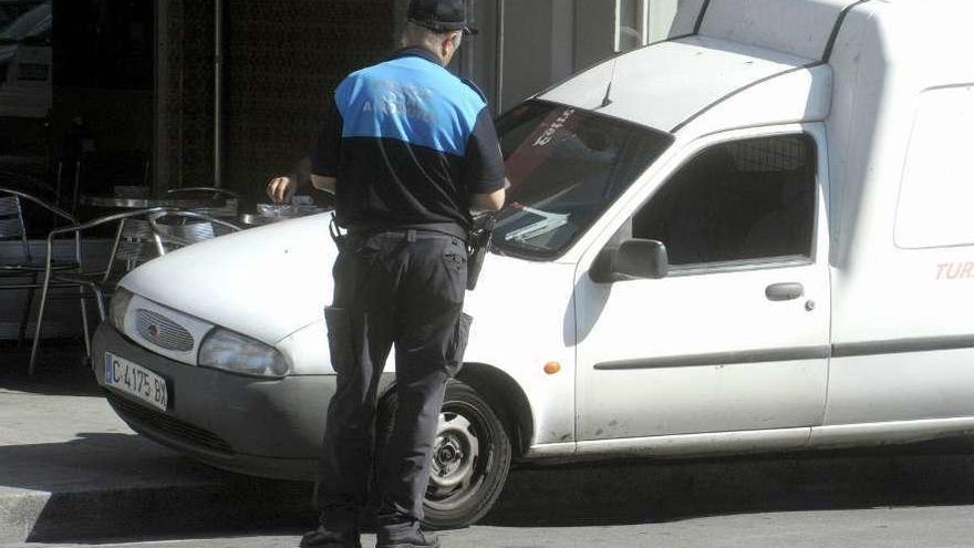 Un policía multa a un coche mal aparcado.