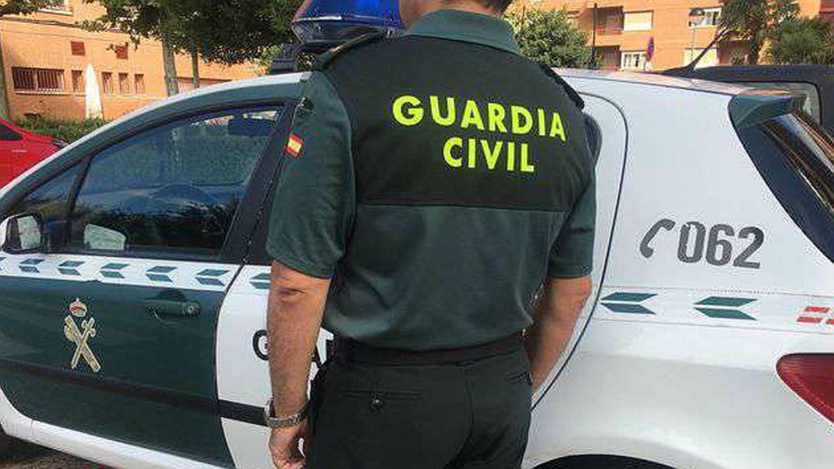 Un guardia civil, junto a un coche del instituto armado.