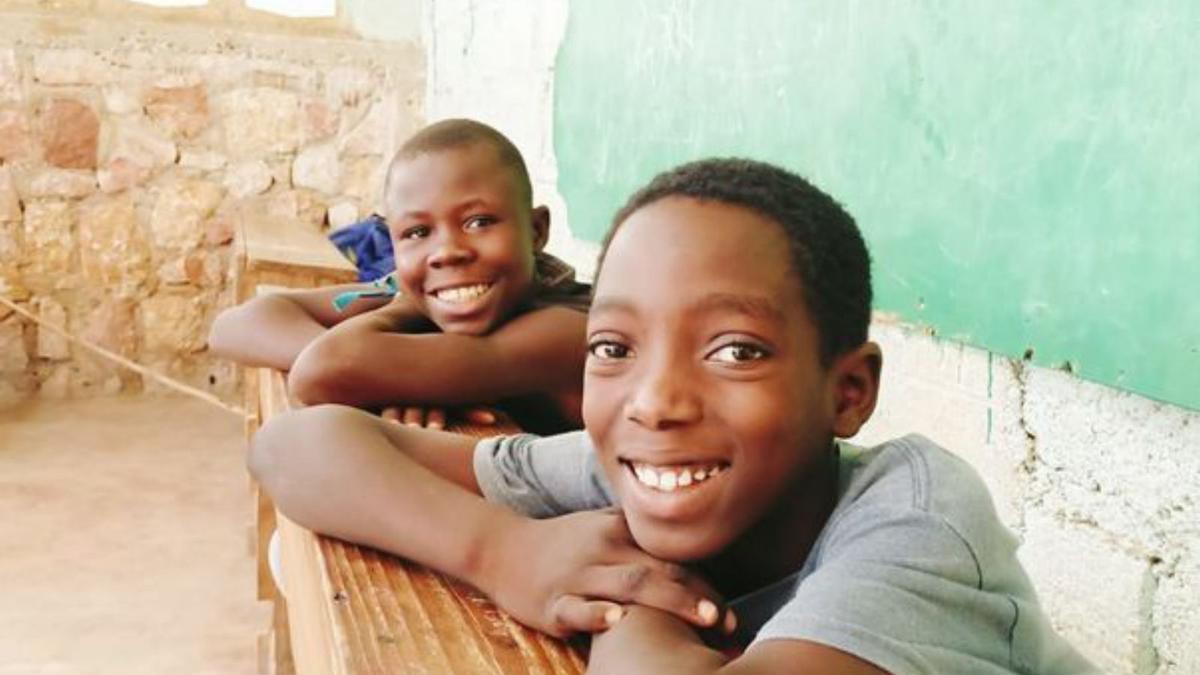 Dos chicos sonríen desde una de las clases del campamento.